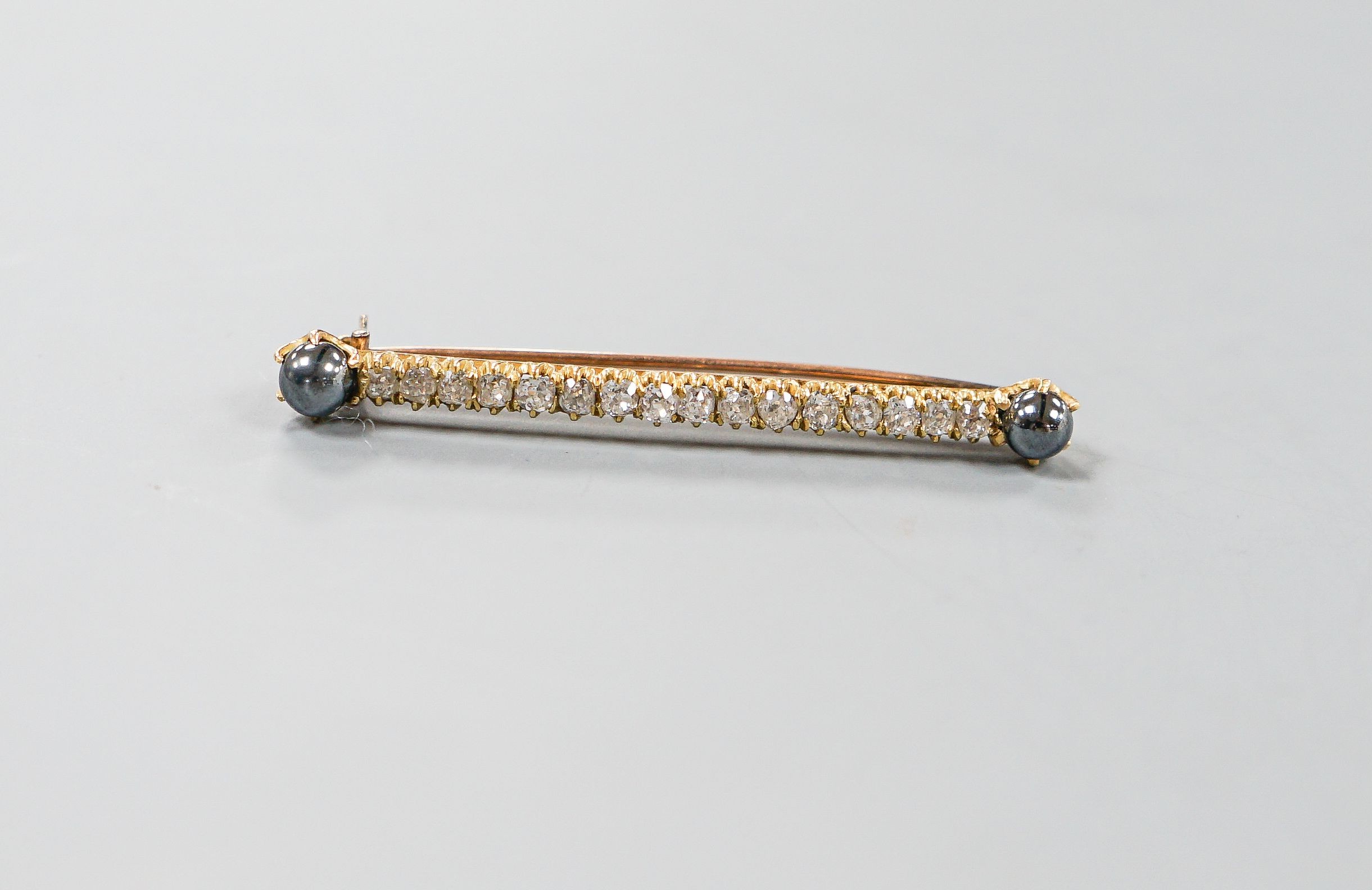 A yellow metal, two stone hematite and sixteen old cut diamond set bar brooch, 52mm, gross weight 5 grams.